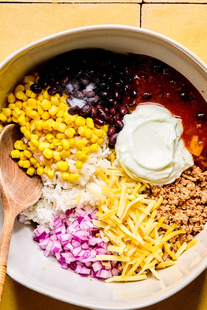 Ingredients for Cheesy Turkey Taco Rice Bake add to the skillet of ground turkey.