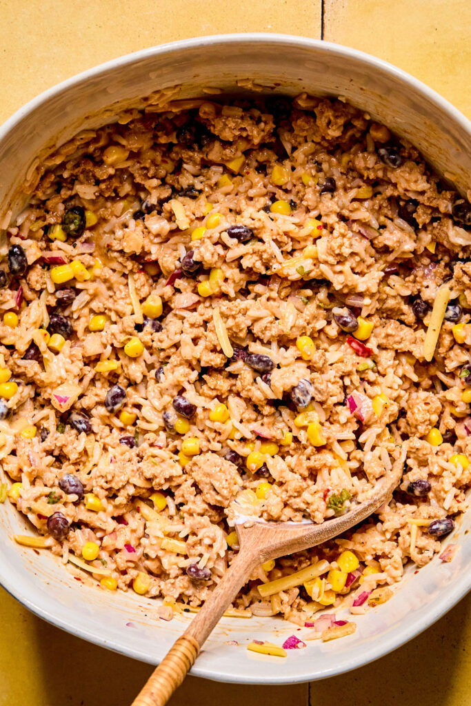 Ingredients for Cheesy Turkey Taco Rice Bake combined together in a skillet.