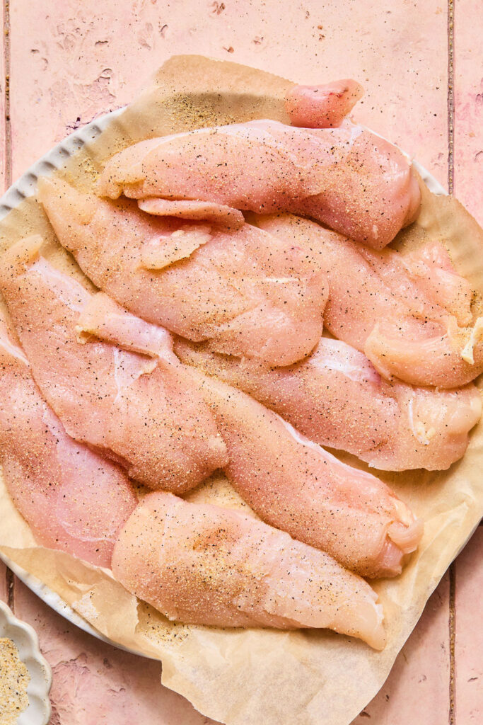 Raw chicken tenderloins on a cutting board.