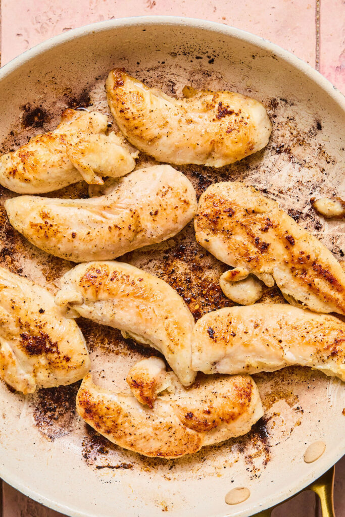 Cooked chicken tenderloins in a skillet.