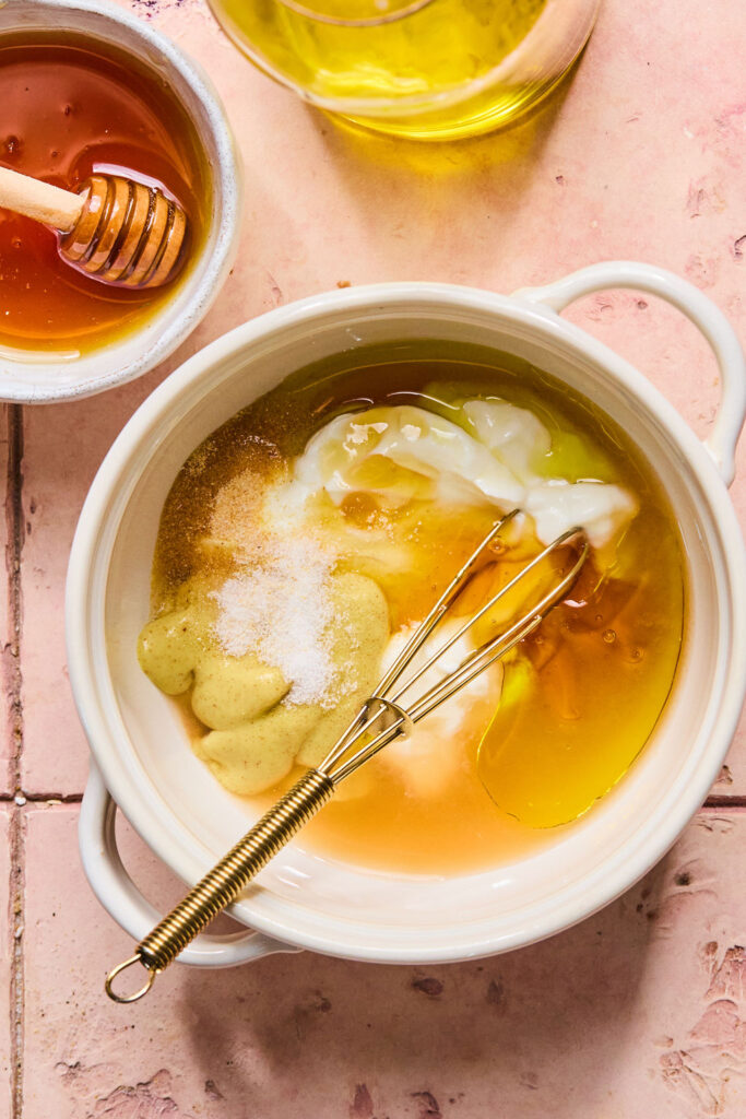 Dressing ingredients in a small bowl with a whisk.
