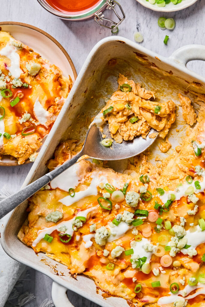 Buffalo Chicken Enchilada Bake in a square baking dish with a spoon.