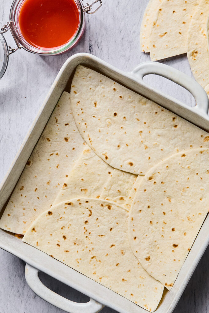 Tortila halves in a square baking dish.