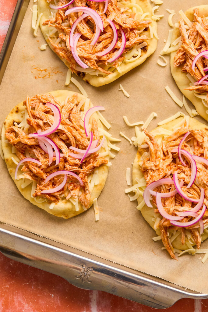  Buffalo Chicken Flatbread on a baking sheet with parchment paper before being baked.