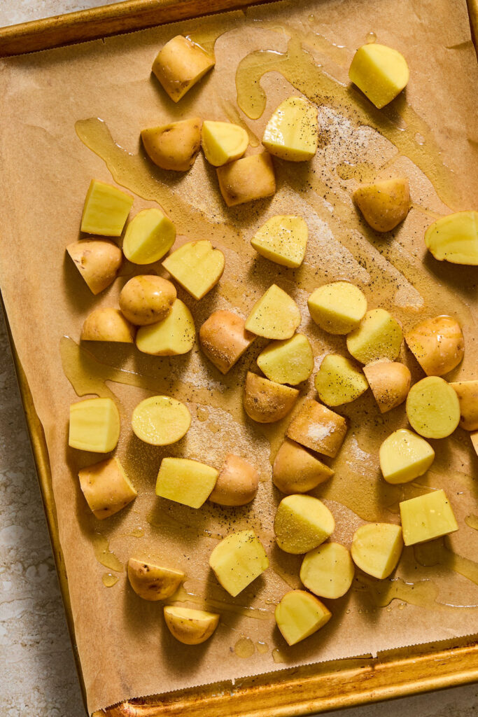Quartered potatoes on a baking sheet.