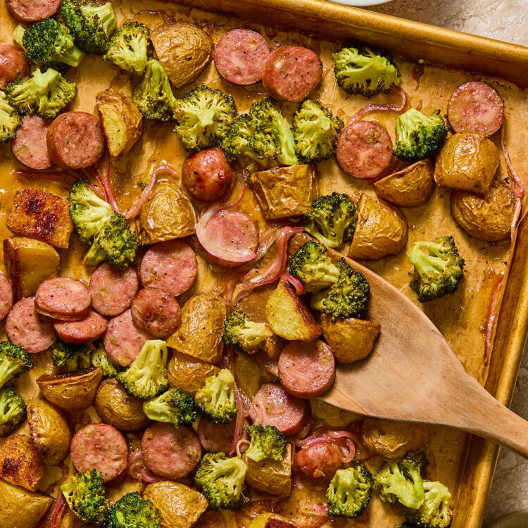 Honey Mustard Chicken Sausage and Potato Sheet Pan on a baking sheet with a wooden spoon.