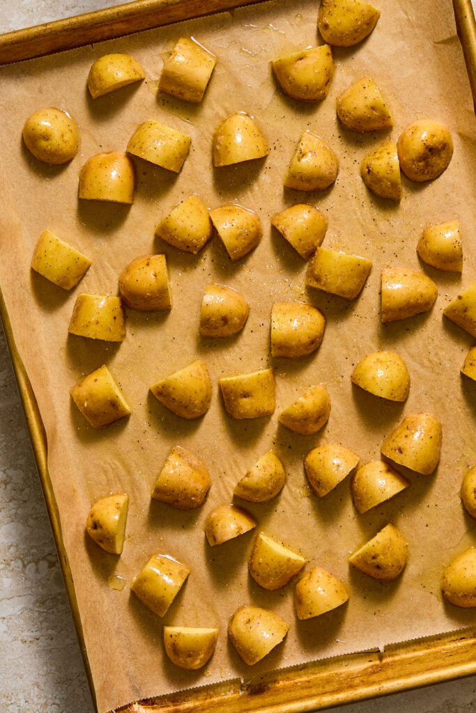 Quartered potatoes on a baking sheet.