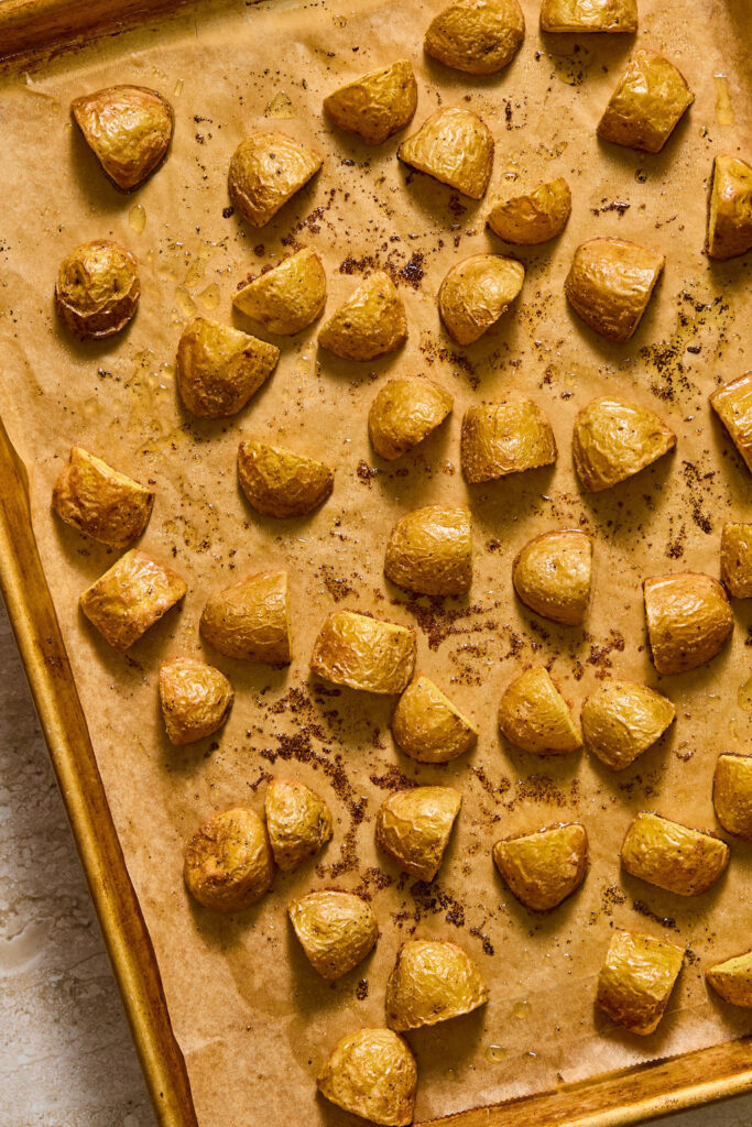 Quartered potatoes on a baking sheet after being baked.