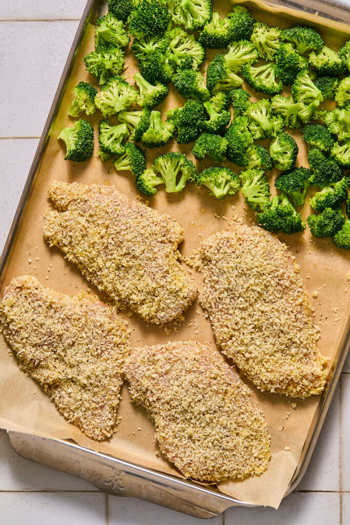 Breaded chicken cutlets and broccoli on a sheet pan.
