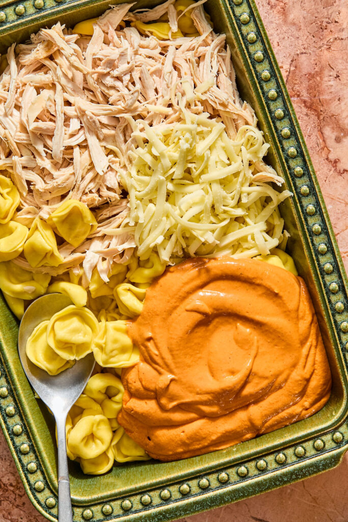 Ingredients for Chicken Parmesan Tortellini Bake in a baking dish before being combined.