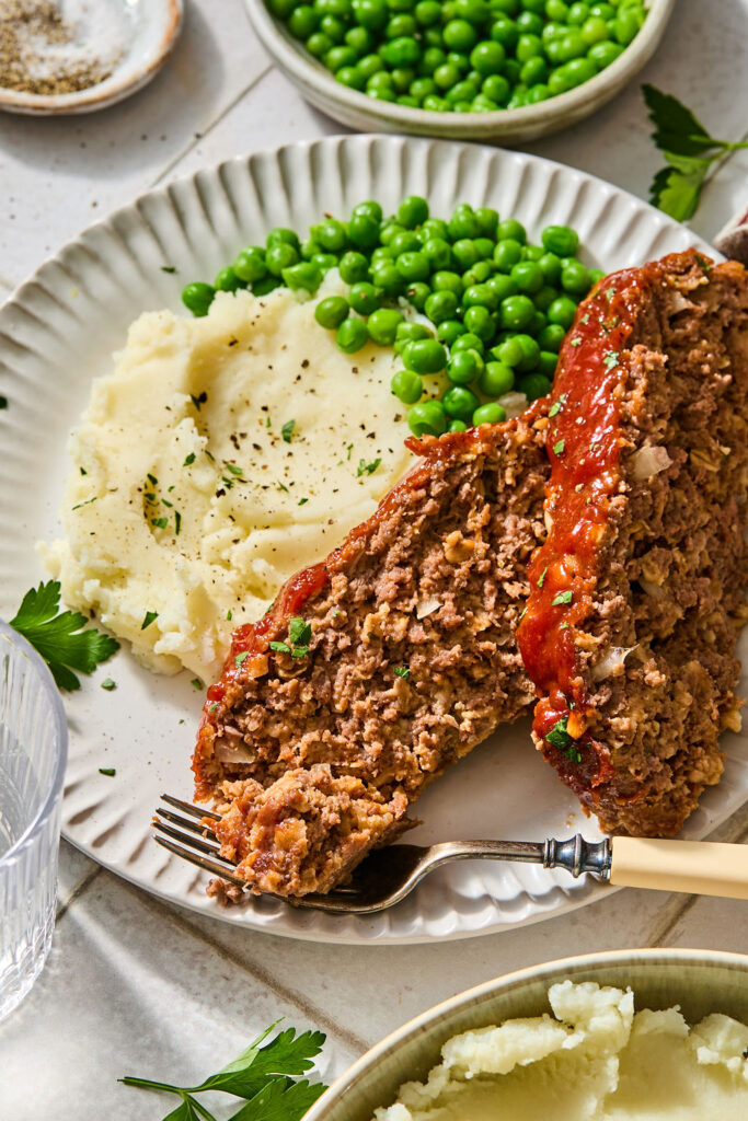 Meatloaf with Oats with mashed potatoes and peas on a plate.