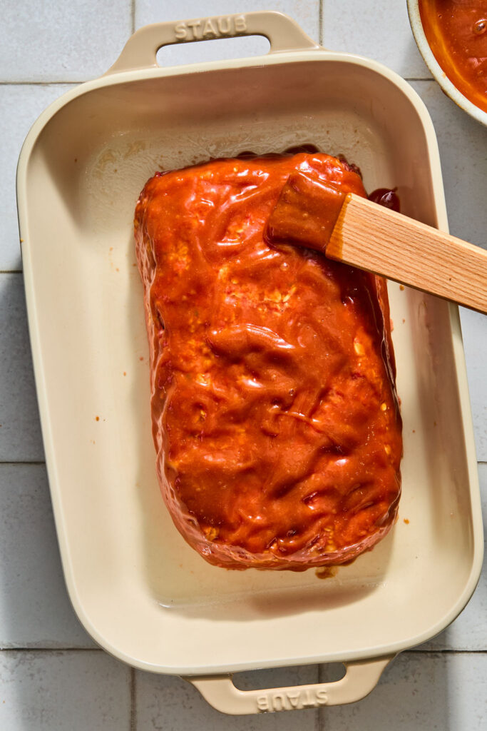 Meatloaf with Oats being topped with sauce.