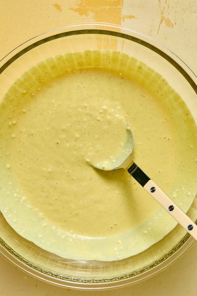 Ingredients for honey mustard mixture in a bowl with a spoon.